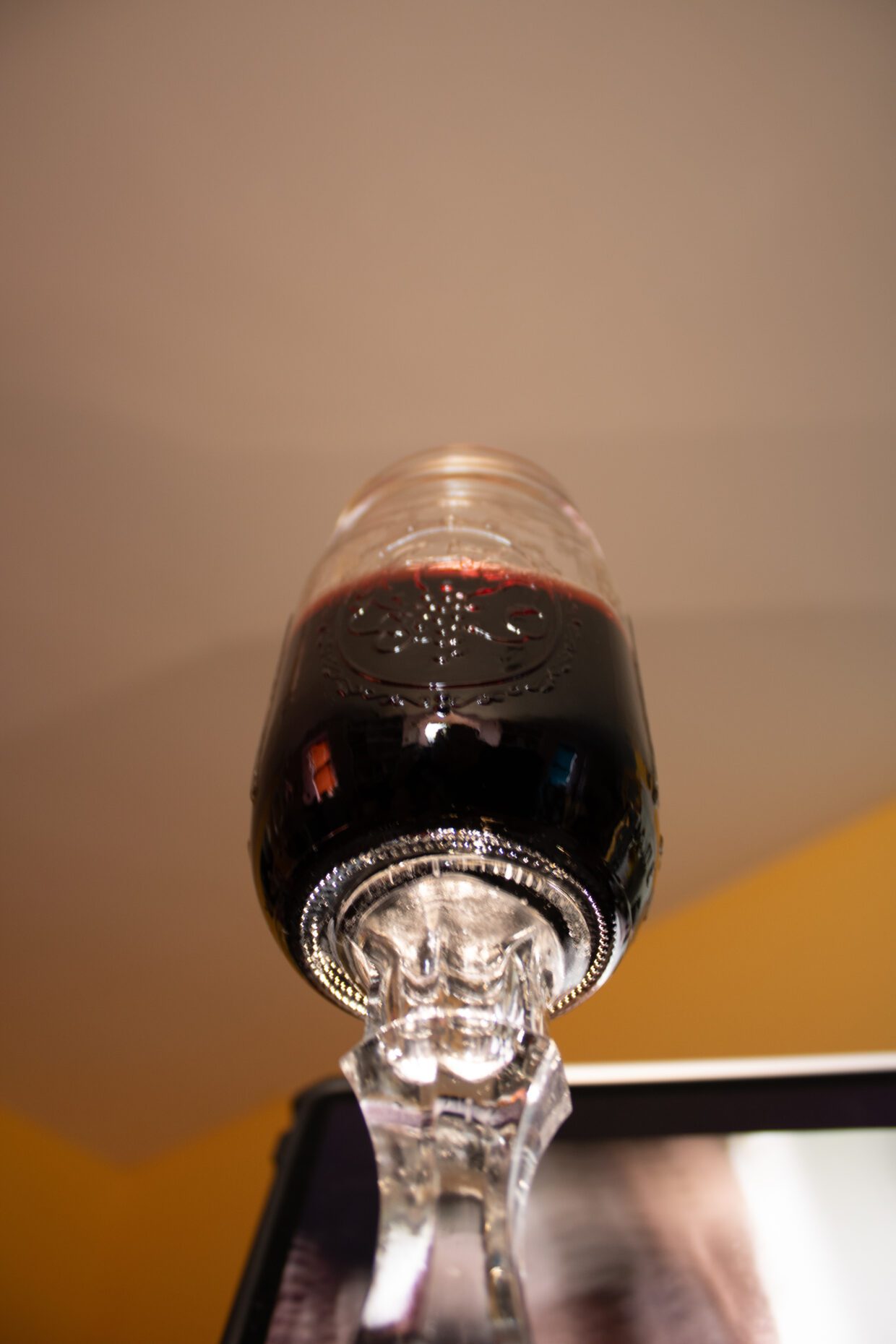 A glass of red wine on a table at home, with warm lighting and soft background ambience